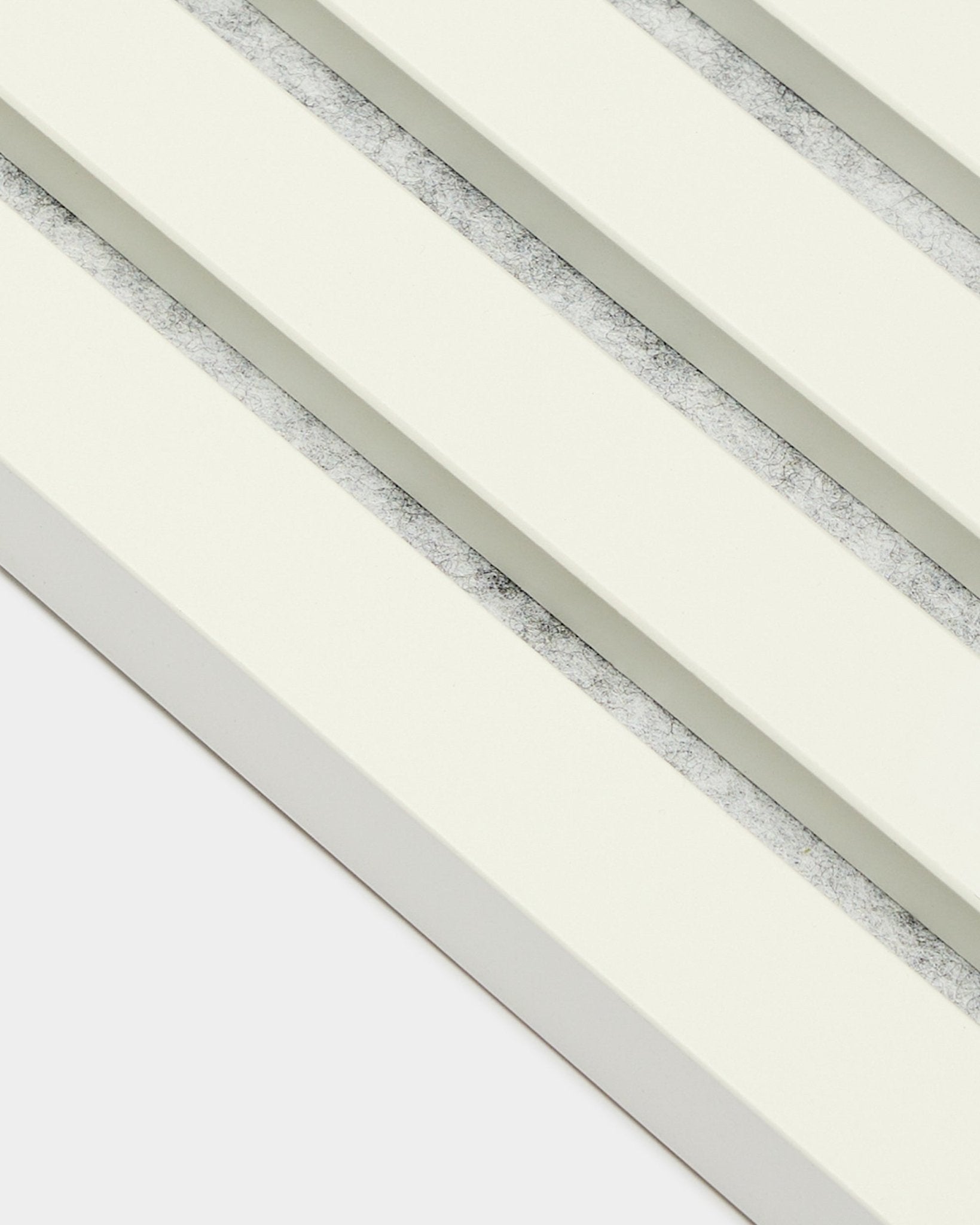 Vier WoodUpp Akupanel Eindlamel/Snow akoestische panelen (2,2 cm), diagonaal geplaatst, met gebroken witte latten en grijze tussenruimtes met textuur in een Scandinavische stijl.